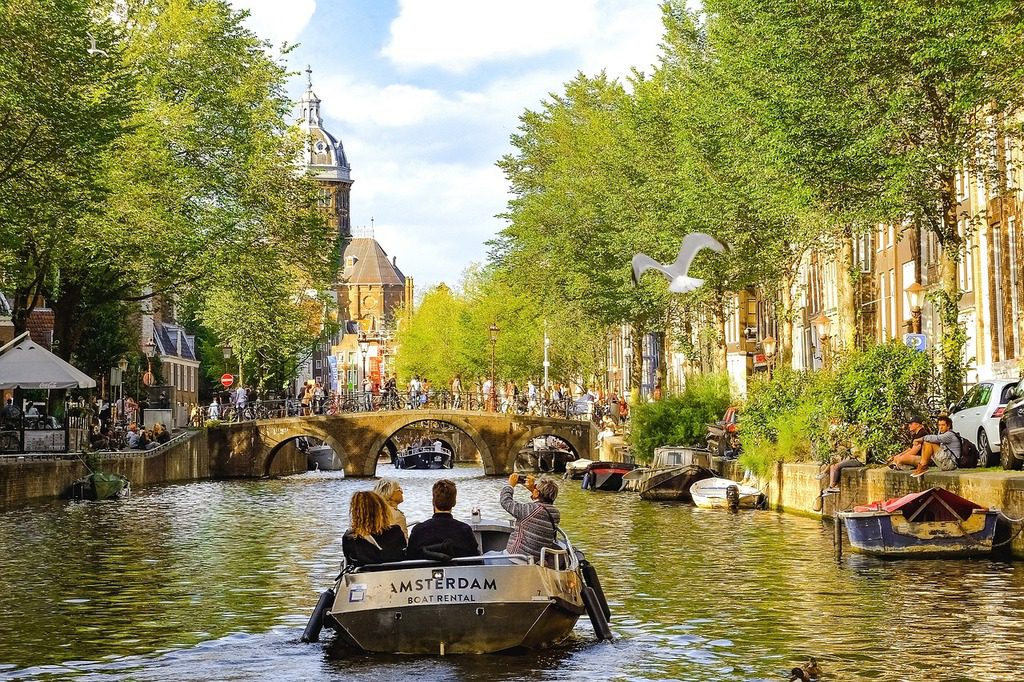 People take a rental boat down a canal in Amsterdam